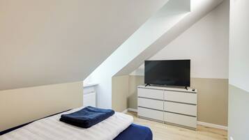 Un dormitorio moderno con cama, televisor de pantalla plana y cómoda blanca.