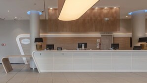 Een modern receptiebalie met een wand van houten panelen, twee zwarte lampen, en een bord met de tekst 'Hampton'.