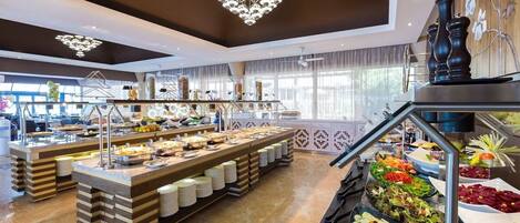Een buffetopstelling met meerdere themastations, waaronder salades, fruit en diverse gerechten.