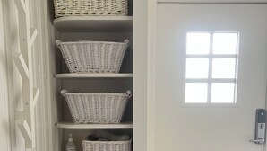 A white interior with a door, a window, and a set of shelves with wicker baskets.