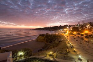 A coastal view with a beach, a staircase leading down to the shore, and a lit pathway. - First-Class Service in Praia da Oura! 1BR Apartment w/ Kitchenette | 3 Units (Albufeira)