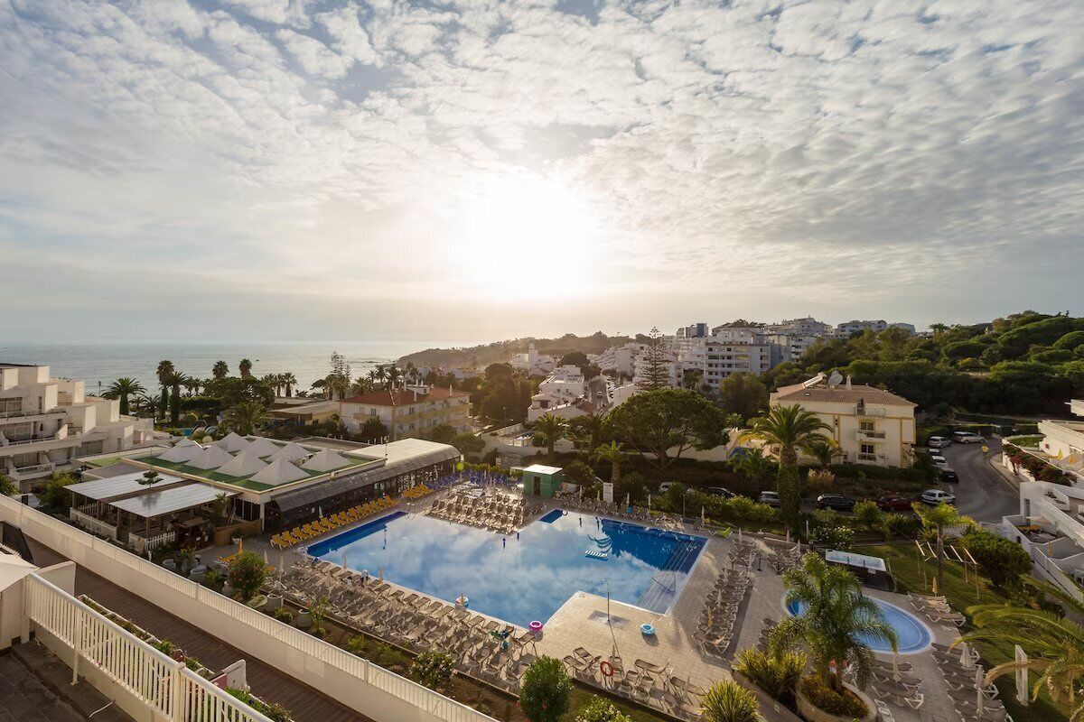 Een resort met een groot zwembad, diverse loungegedeeltes en uitzicht op zee.