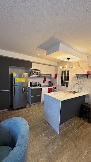 Una cocina moderna con una isla central, electrodomésticos de acero inoxidable y un microondas.