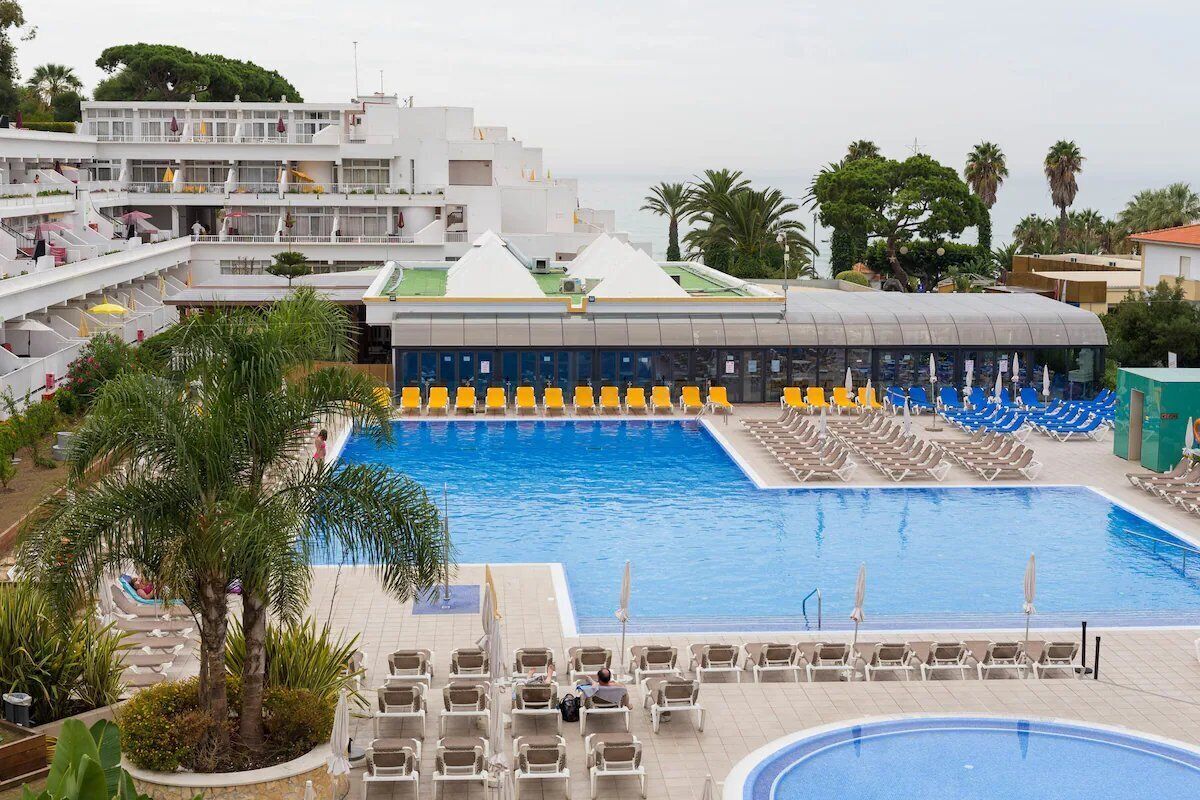 A large swimming pool with multiple sun loungers and a covered area.