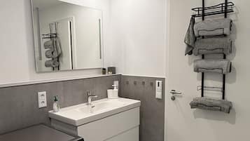 Une salle de bain moderne équipée d’un lave-linge intégré, d’un lavabo et d’un porte-serviettes.