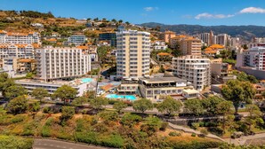 Un paysage urbain côtier avec des immeubles à plusieurs étages, dont un hôtel imposant doté de balcons et d’une piscine sur le toit.