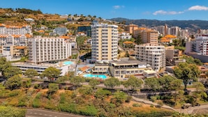 Paesaggio costiero con edifici a più piani, tra cui un hotel in evidenza con balconi e piscina sul tetto.
