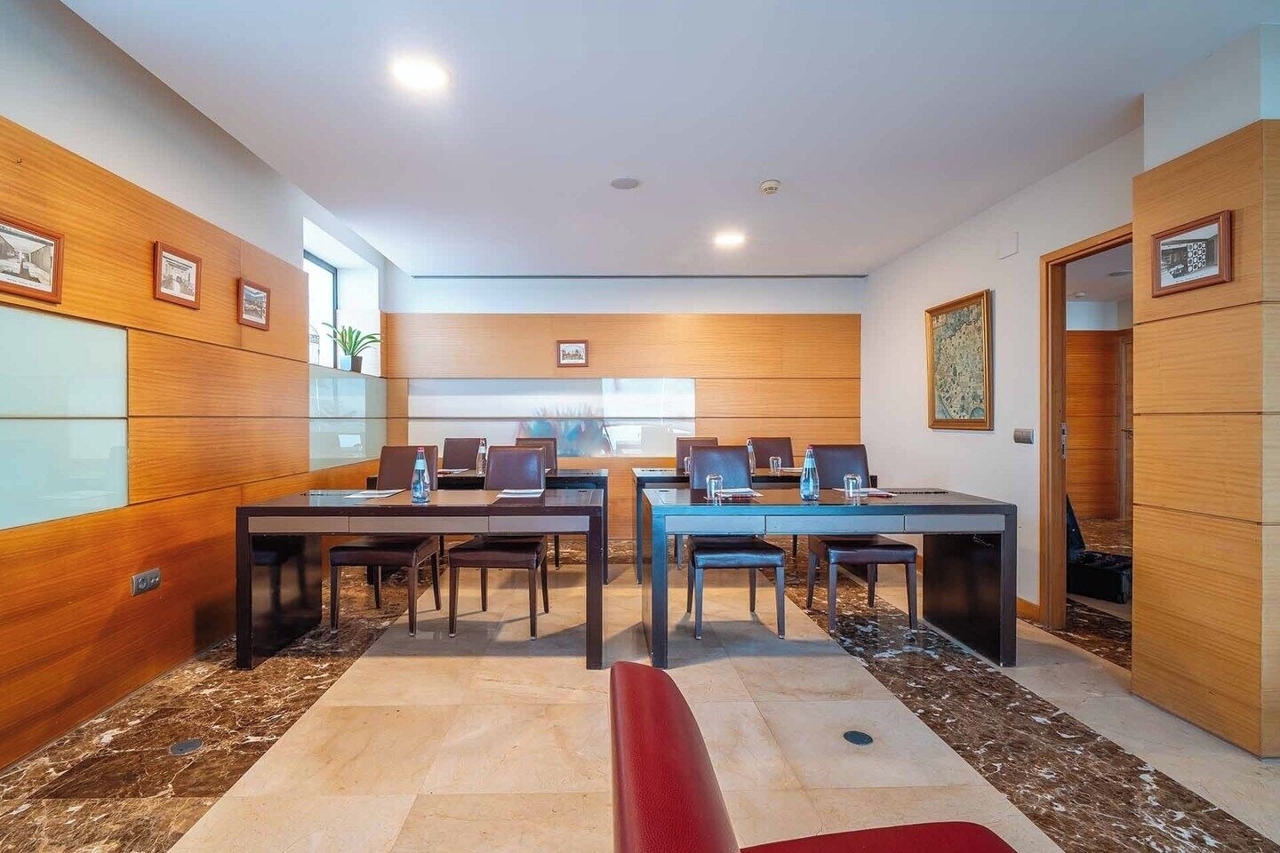 Une salle de conférence avec deux tables, des chaises et un banc rouge.