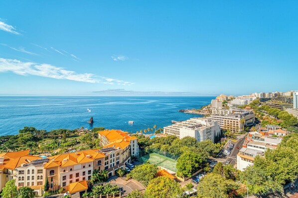 A coastal cityscape with buildings, a clear blue sky, and a view of the sea.