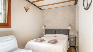 A bedroom with a bed, two bedside lamps, a wooden ceiling, and a brick wall. - Basilica Prestige 5* Residence, luxury and comfort (Vicenza)