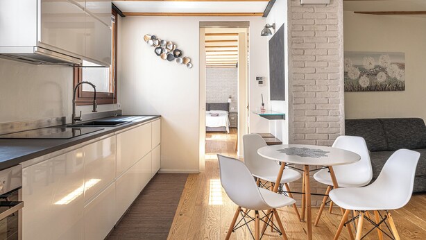 A modern kitchen with a built-in oven, a sink, and a dining area with a round table and four chairs. - Basilica Prestige 5* Residence, luxury and comfort (Vicenza)
