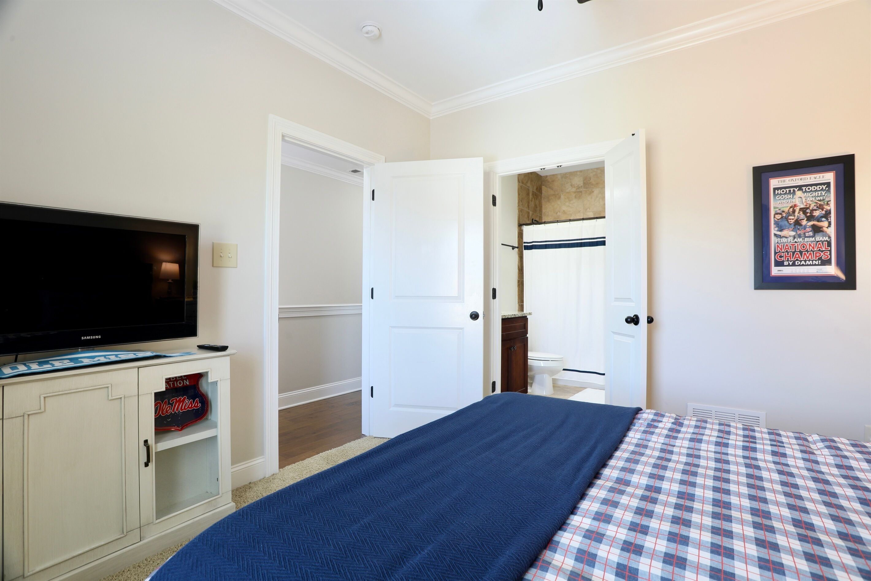A hotel room with a bed, a television, a cabinet, and a door leading to a bathroom.