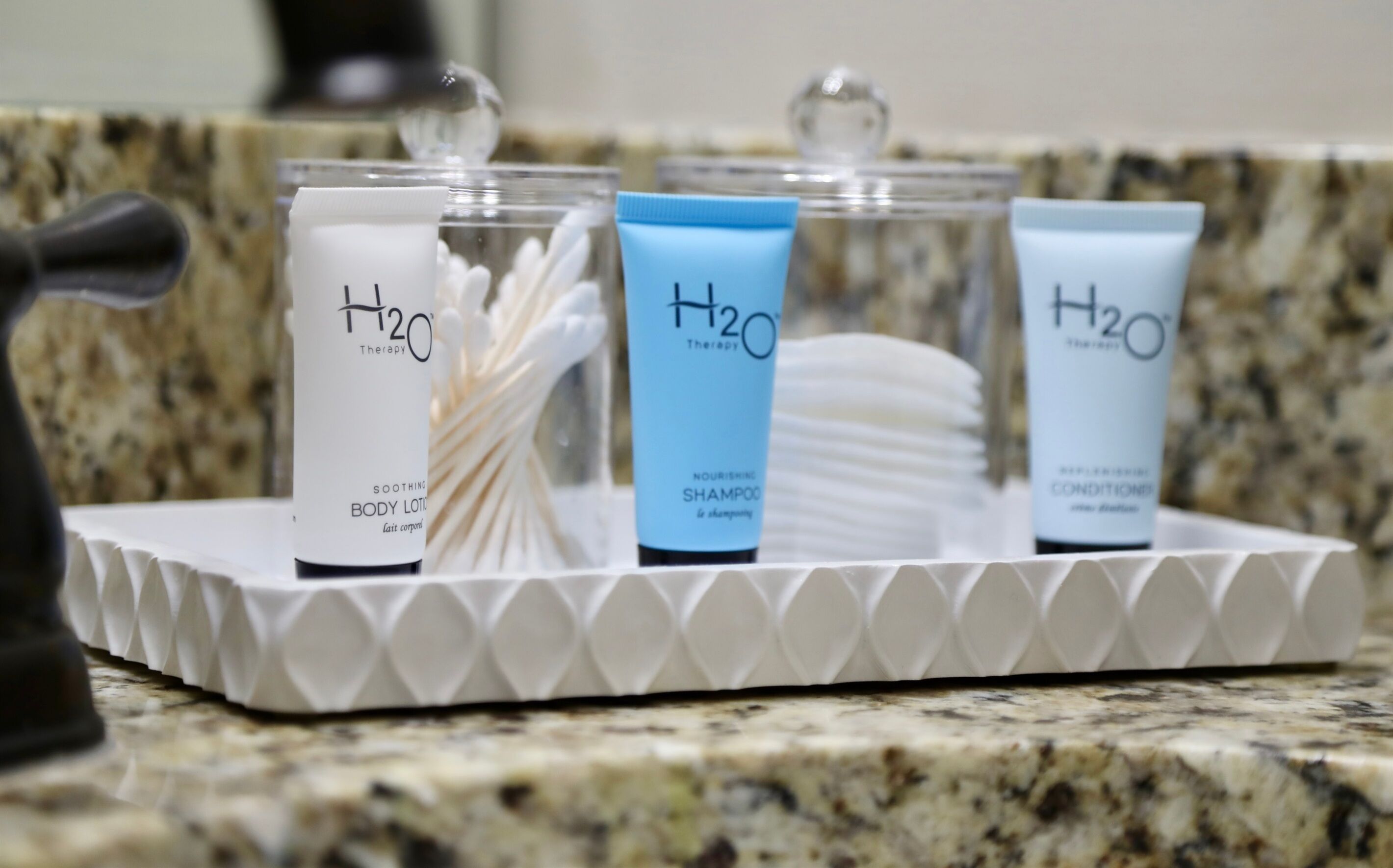 A tray with three H2O Therapy products: body lotion, shampoo, and conditioner.