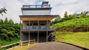 A modern two-story building with a balcony, a staircase, and a paved entrance area. - 🏔️ Apres All Day 🌙 Rooftop Mountain Views, Putting Green, Hot Tub & Arcade (Gatlinburg)