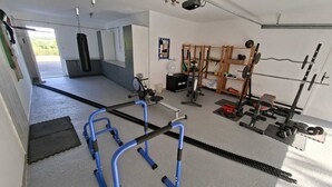 Un gimnasio con equipo de ejercicio, un saco de boxeo y un espejo.