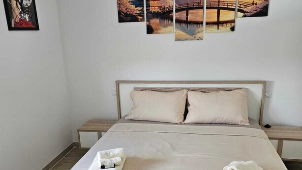 Una habitación de hotel con una cama grande, dos mesitas de noche y una pared decorada con tres cuadros enmarcados.