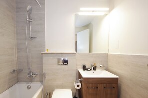 Ein Badezimmer mit Badewanne, Toilette, Waschbecken und Spiegel.