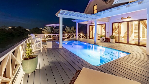 Eine Holzterrasse mit Swimmingpool, Liegestühlen und einem überdachten Patio-Bereich.