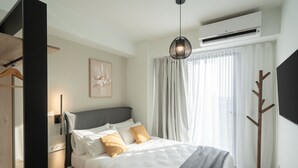 A modern bedroom with a bed, bedside table, and a coat rack.