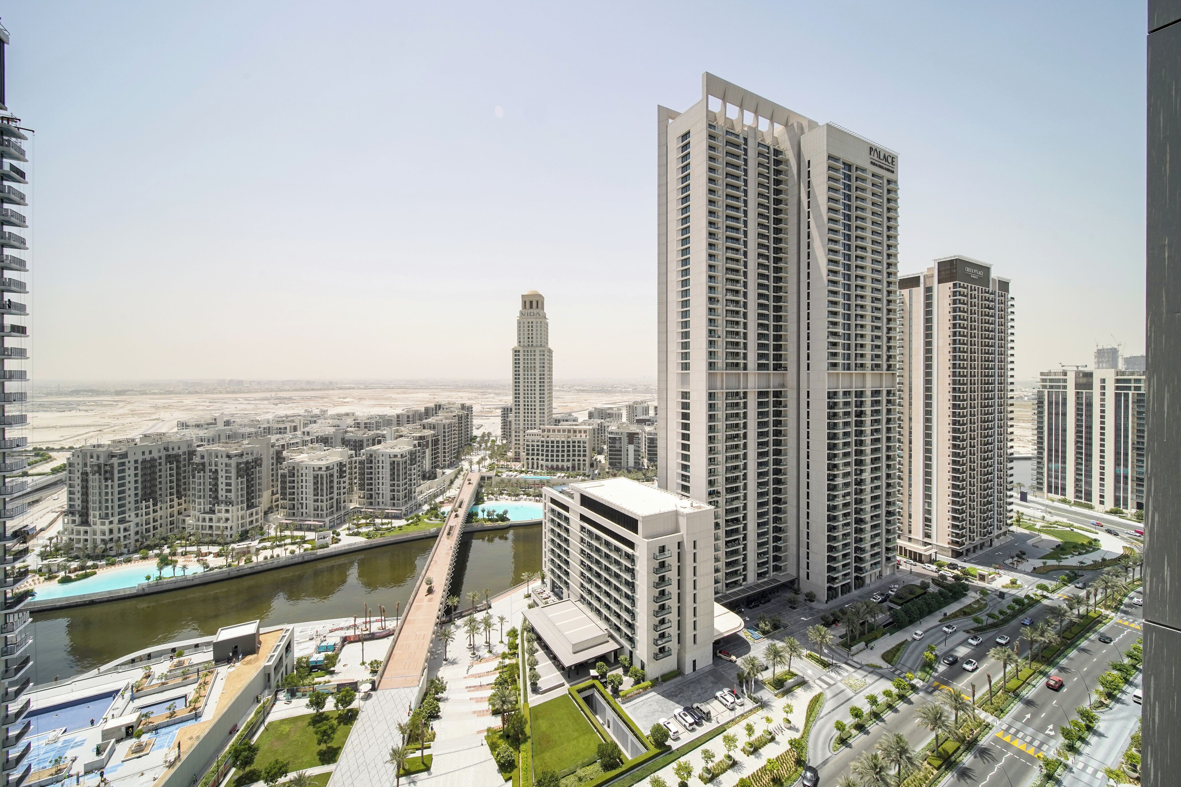 Un immeuble résidentiel de grande hauteur au design moderne, entouré d’autres immeubles de grande hauteur, d’un plan d’eau et d’un espace urbain bien aménagé.