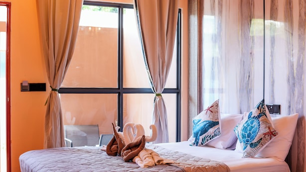 A hotel room with a bed, curtains, a window, and a chair. - Ari Stay Thoddoo  (Thoddoo)