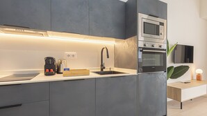 Egy modern konyha szürke színű szekrényekkel, beépített sütővel, mikrohullámú sütővel és kávéfőzővel.