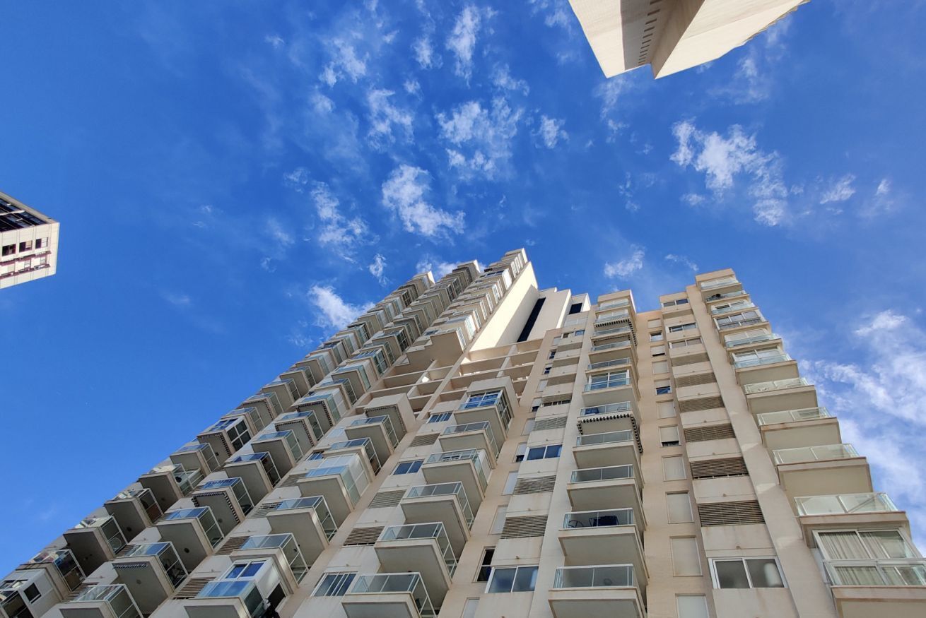 Un edificio alto con varios balcones y un cielo azul despejado.