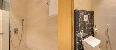 Un baño con cabina de ducha de vidrio, lavamanos de mármol y un inodoro.
