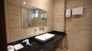 A modern bathroom with a large mirror, a white sink, and a black countertop. - The Elevate Hotel (New Delhi)