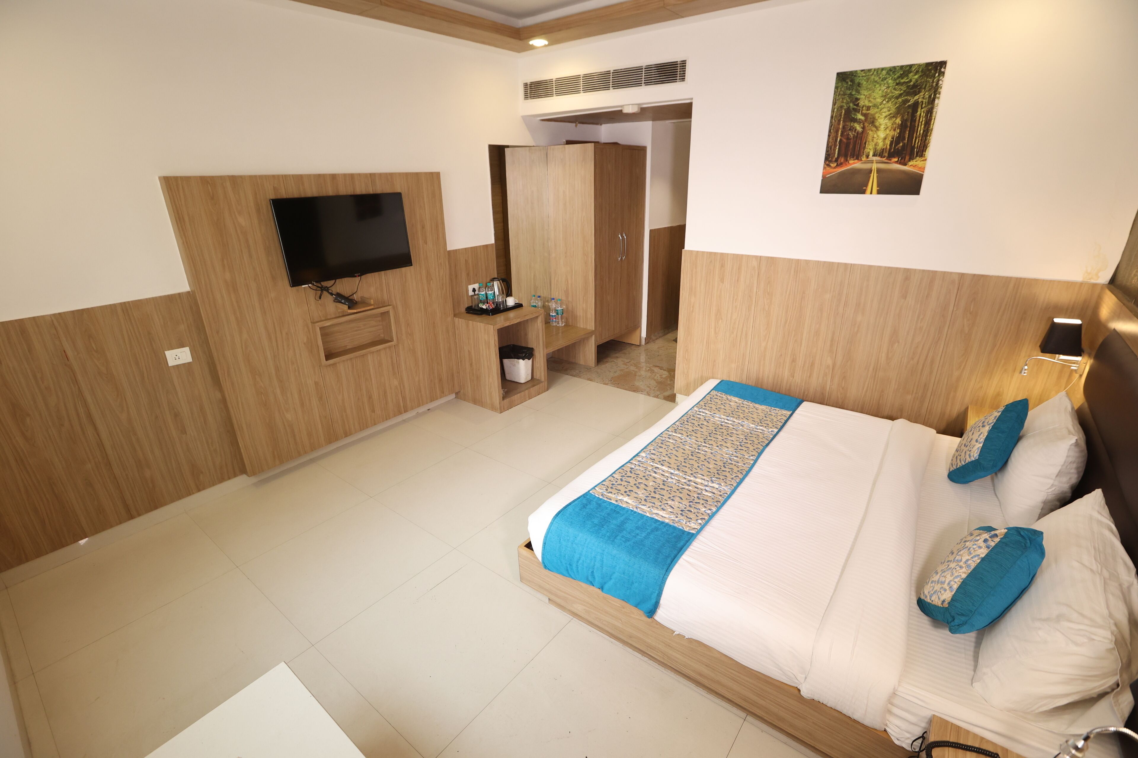 Een hotelkamer met een groot bed, een televisie, een kledingkast en een zithoekje.