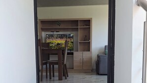 Un corridoio che conduce a una zona pranzo con un tavolo e sedie in legno, una pianta in vaso e un tappeto con impronte.