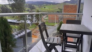 Un balcone con vista su un paesaggio rurale, un tavolo e una sedia.
