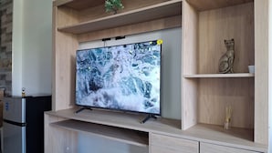 Una cucina moderna con TV integrata, mobili in legno ed uno scaffale decorativo con una piccola pianta e una statuina.