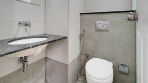 Casa de banho com lavatório, espelho, chuveiro e sanita.