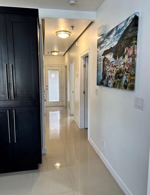 A hallway with a black door, a painting, and a ceiling light. - Luxe 3BR/2BA Condo. Near Mall, Airport & Hospitals (McAllen)