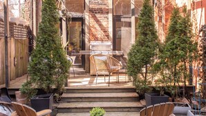A brick building with a wooden deck, two wooden chairs, and potted plants. - Elegant Brownstone Bathurst/King streets (Toronto)