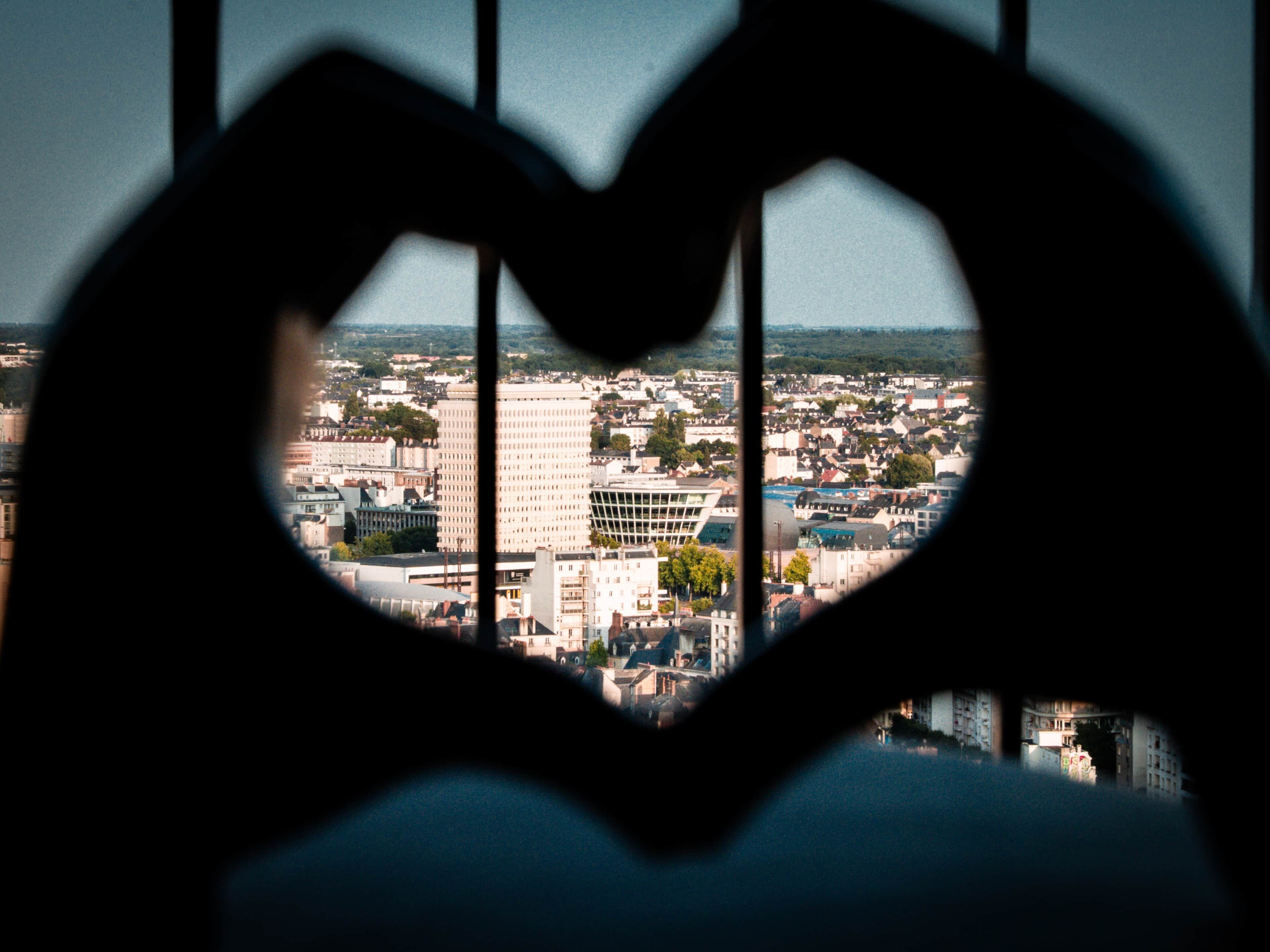 Eine herzförmige Silhouette vor einem Fenster, das einen Blick auf die Stadt bietet.