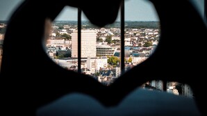 Silueta a forma di cuore su una finestra, con vista sullo skyline della città.
