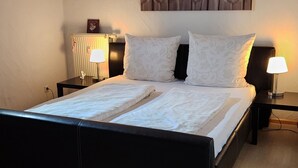 Un dormitorio con una cama grande, dos mesitas de noche, una lámpara de pared y una luz en el techo.