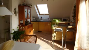 Una cocina con tragaluz, armarios de madera, una zona de comedor con una silla y una cama.