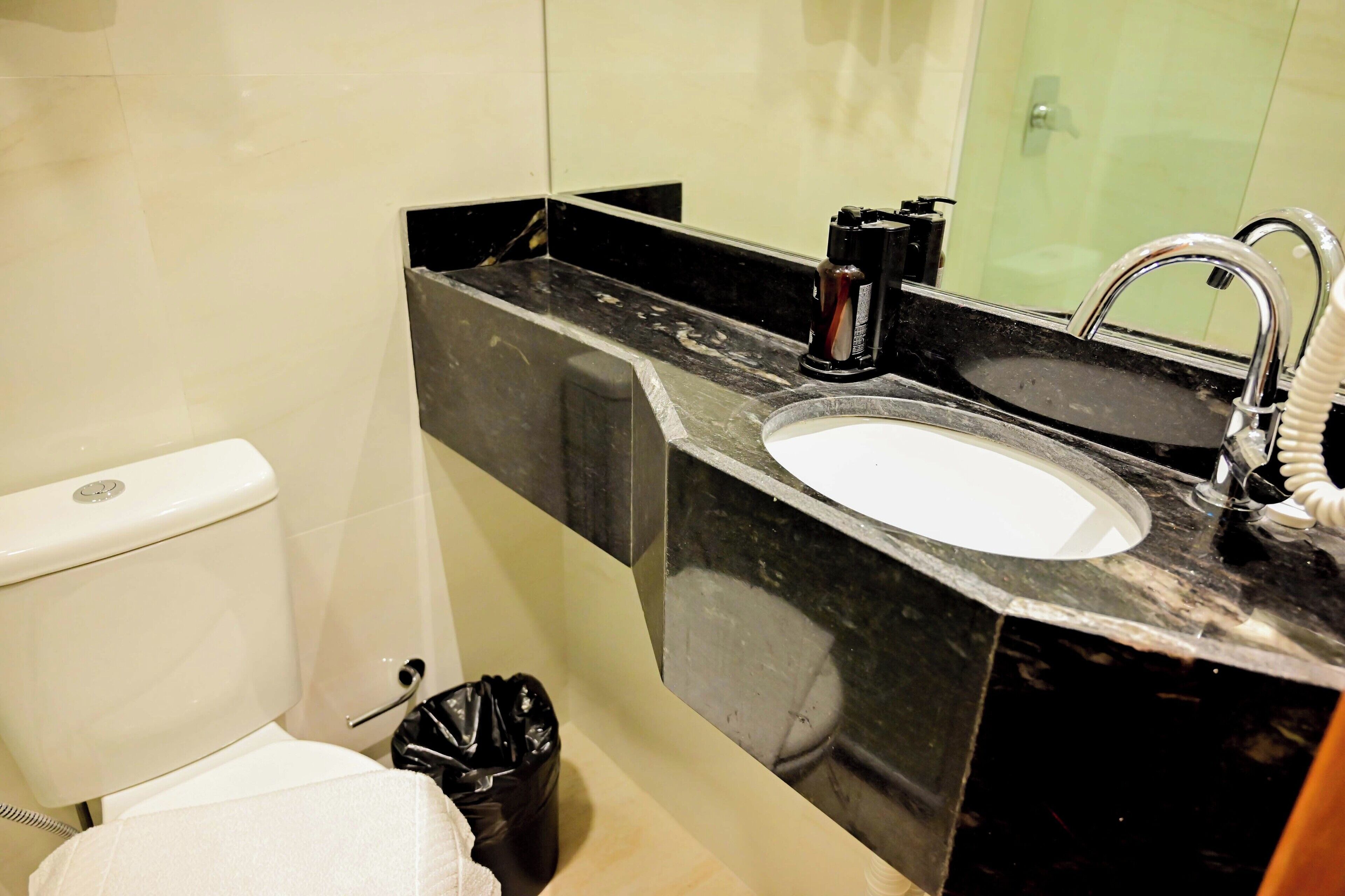 Een badkamer met toilet, wastafel en spiegel.