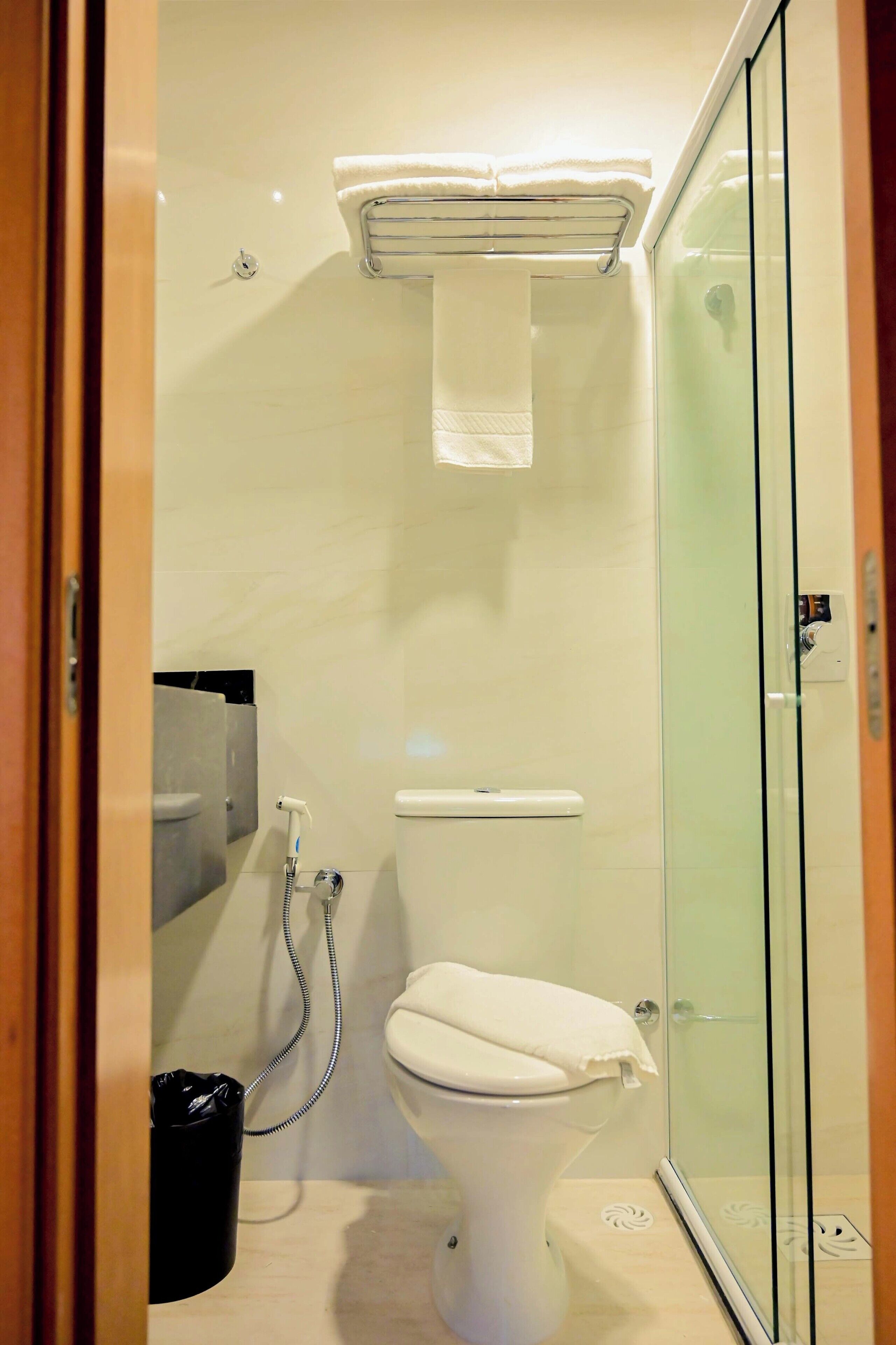 Une salle de bain équipée de toilettes, d’une douche à parois de verre et d’une poubelle.