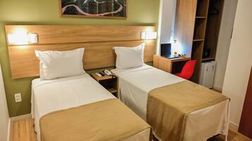 Habitación de hotel con dos camas, un escritorio con una computadora portátil, una silla roja y un cuadro en la pared.
