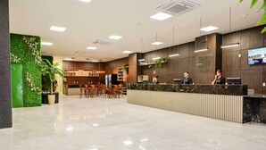 A modern hotel lobby with a reception desk, seating area, and a green wall with plants. - Bristol Marambaia Belem (Belém)