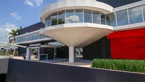 A modern building with a curved glass structure, a red facade, and a landscaped area with grass. - Bristol Marambaia Belem (Belém)