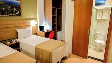 Une chambre d’hôtel avec deux lits, un bureau avec un ordinateur portable, une chaise rouge, une armoire et un espace douche.