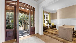 A room with a wooden door, a sofa, a lamp, and a wooden cabinet. - Pristine getaway with tranquil views (Kiawah Island)
