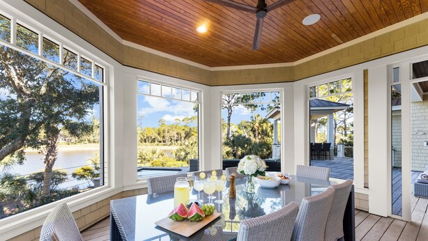 A sunlit dining area with a table set for four, large windows, and a view of a lake. - Pristine getaway with tranquil views (Kiawah Island)