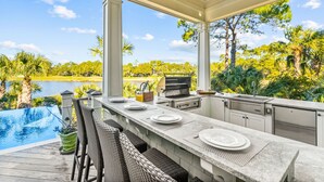 An outdoor kitchen with a view of a lake and trees. - Pristine getaway with tranquil views (Kiawah Island)
