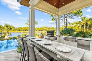 An outdoor kitchen with a view of a lake and trees.